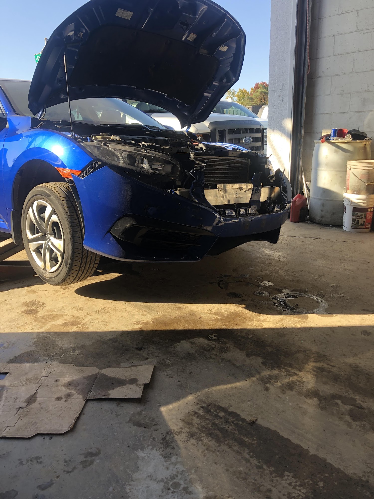 Blue Honda in a shop bay during front-end body work